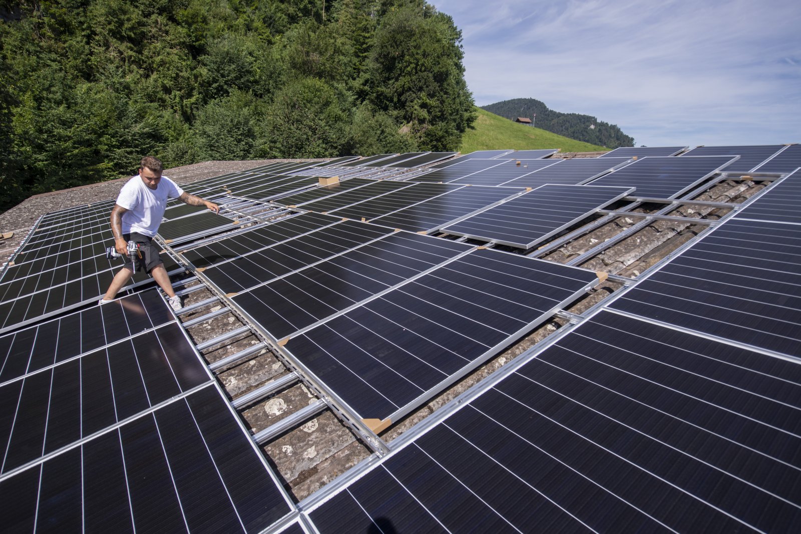 Montage von Solarpanels auf einer Halle in Stans NW. Bild: Keystone