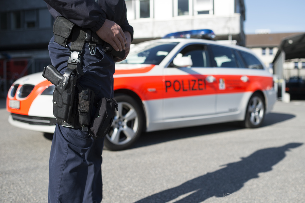 Ein Polizist steht vor einem Dienstfahrzeug der Kantonspolizei Graubünden, aufgenommen am Dienstag, 21. April 2015, in Chur. (KEYSTONE/Gian Ehrenzeller)