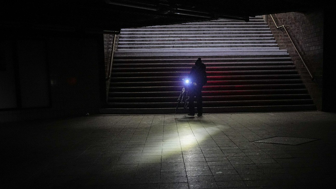 Ein Mann schiebt sein Velo durch das dunkle Berlin. Nur sein Fahrrad hat noch Licht. Bild: Keystone