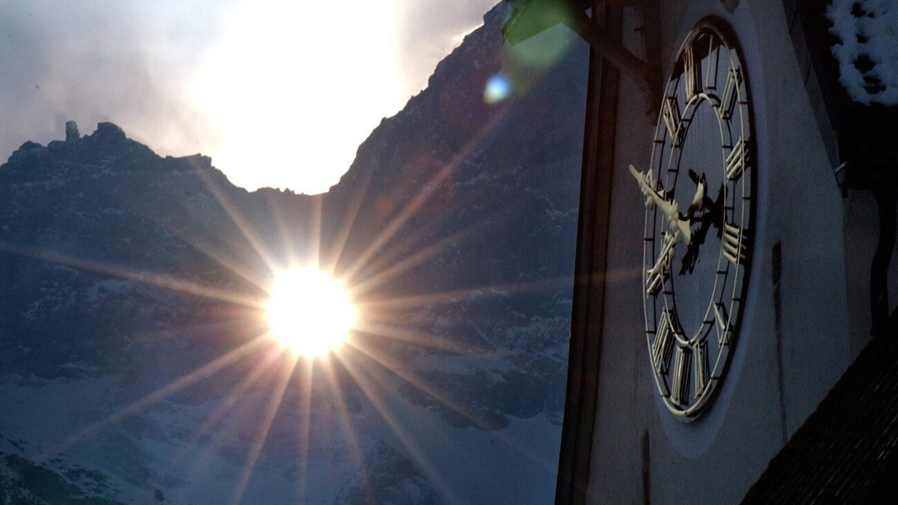 Die Sonne scheint morgens durch das Martinsloch auf den Kirchturm von Elm, Glarus. Bild: Keystone