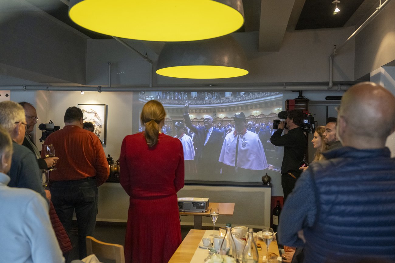 Besucher der Zuger Mitte-Partei beobachten die Vereidigung von Martin Pfister zum Bundesrat während einem Public Viewing. Bild: Keystone