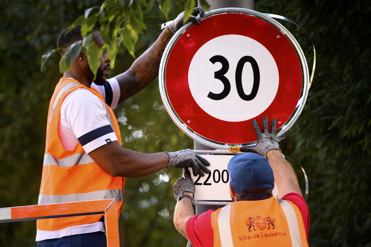 Mitarbeiter der Stadt Lausanne montieren ein Tempo-30-Schild. Seit 2021 gilt in der Innenstadt nachts flächendeckend Tempo 30. (Bild: Keystone)