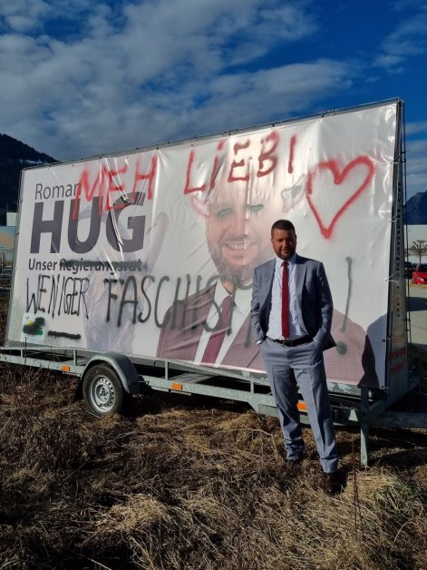 SVP-Regierungsratskandidat Roman Hug (GR) steht vor seinem verwüsteten Plakat in Chur. (Bild: zvg)