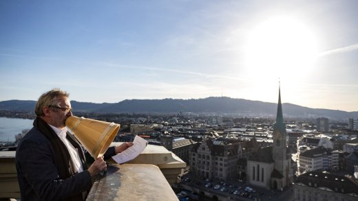 Pfarrer Christoph Sigrist spricht mit einem Trichter den Stadtsegen vom Turm des Grossmuensters in Zuerich