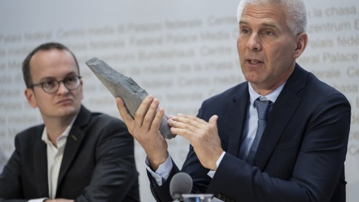 Nagra-CEO Matthias Braun präsentiert an der Medienkonferenz ein Stück Opalinuston. (Links: Martin Neukom, Regierungsrat Zürich, Grüne). Bild: Keystone